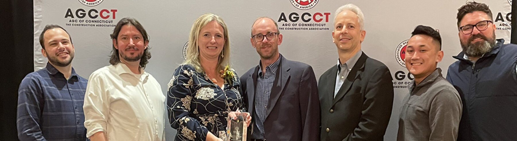 A group of people standing in front of the AGC Subcontractor of the Year banner with an award