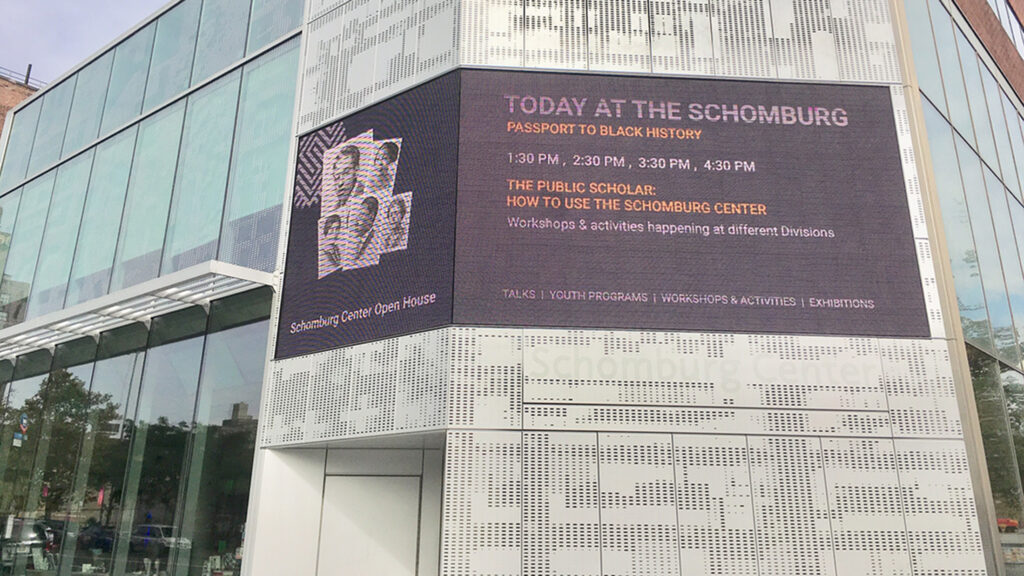 LED display wrapping around the corner of a building. The display is showing content that announces Today at the Schomburg
